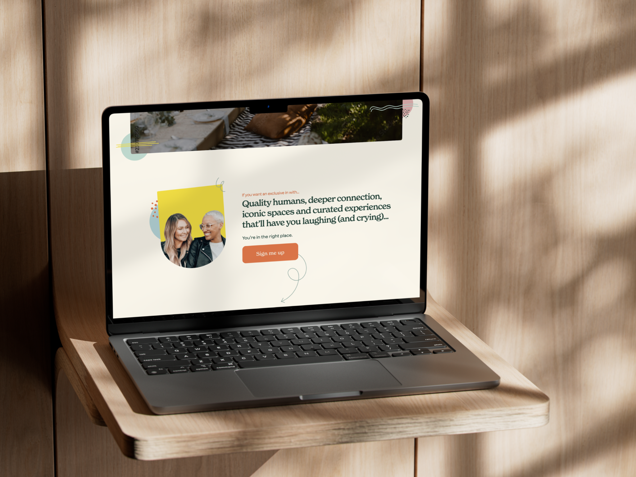 Laptop on a wooden shelf displaying a coaching site about deeper connections and trusted communities.